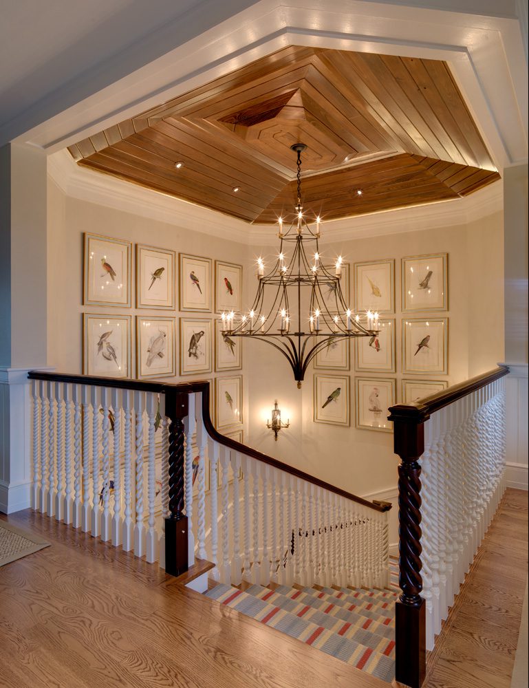A chandelier hanging above the stairs in a home.