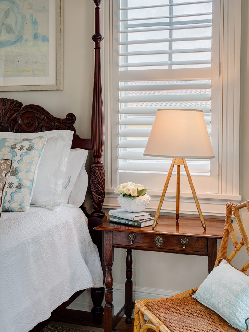 A bedroom with a bed, nightstand and lamp.