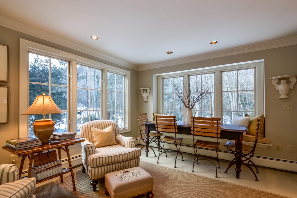 A living room with chairs, tables and windows.