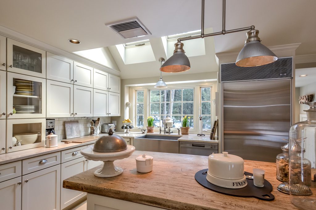 A kitchen with a large window and stainless steel appliances.