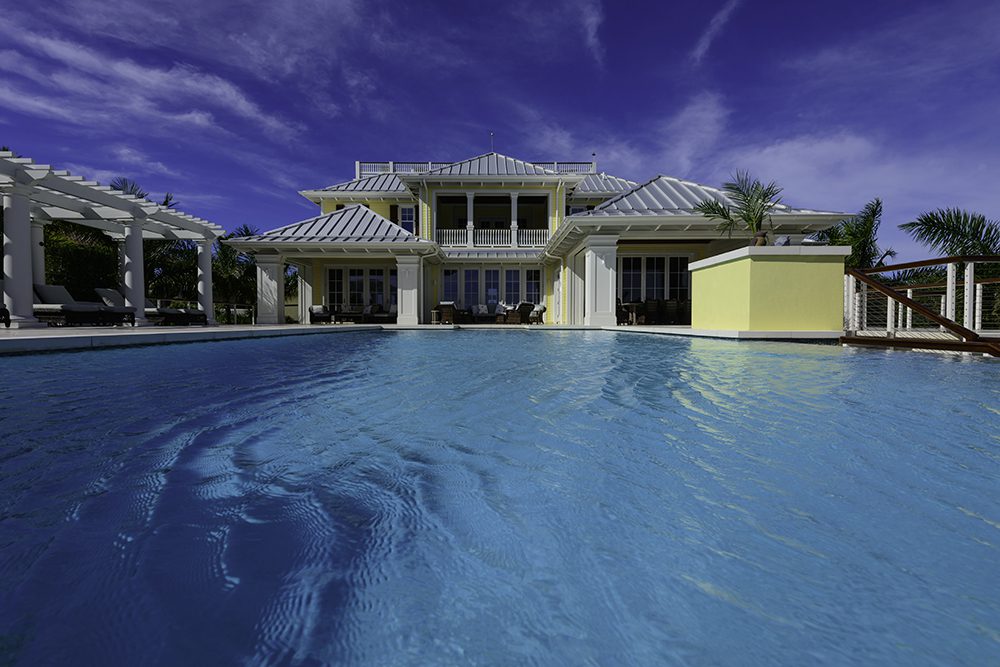 A large pool with a house in the background.