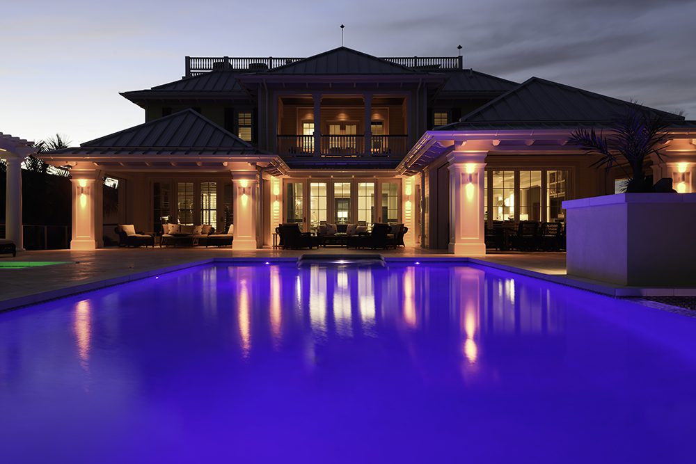 A large pool in front of a house at night.