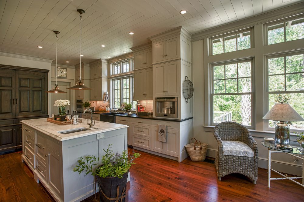 A kitchen with white cabinets and wooden floors.