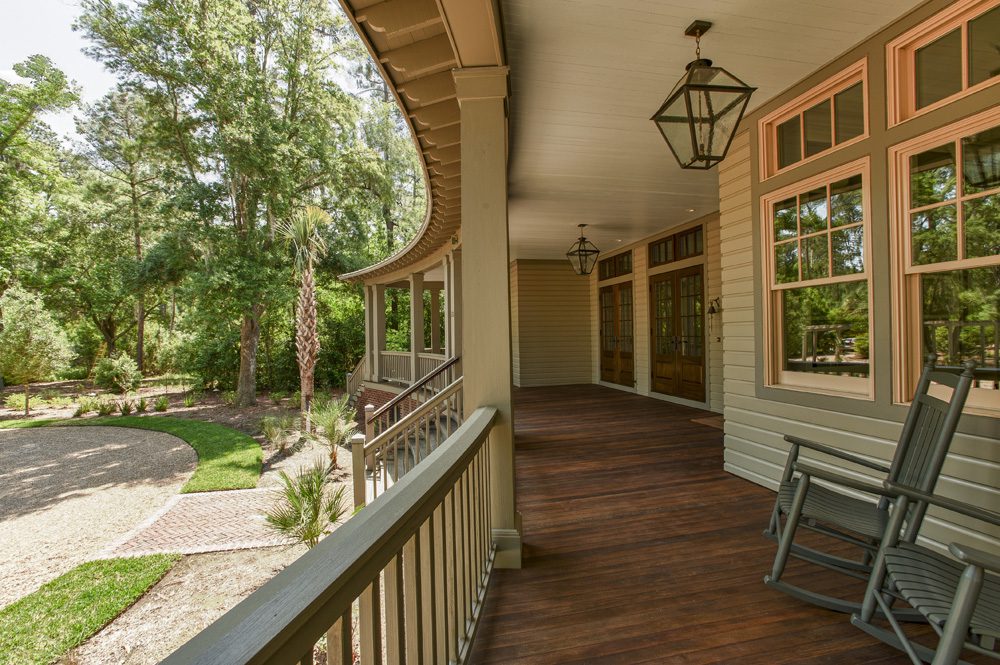 A porch with many windows and trees in the background