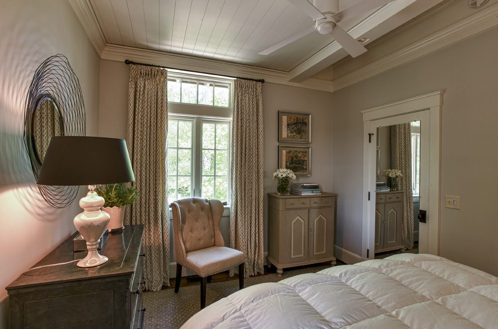 A bedroom with a bed, chair and dresser.